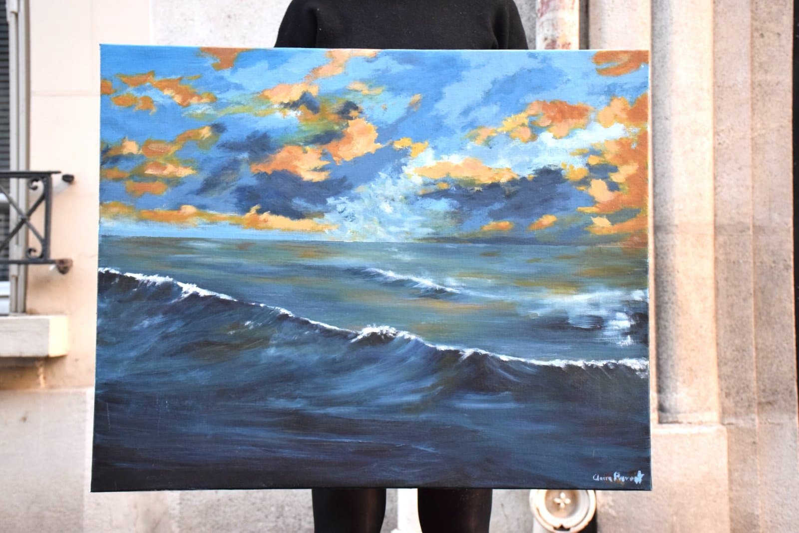 Claire Prevost tenant La vague, une marine où l'écume se brise sous un ciel orangé