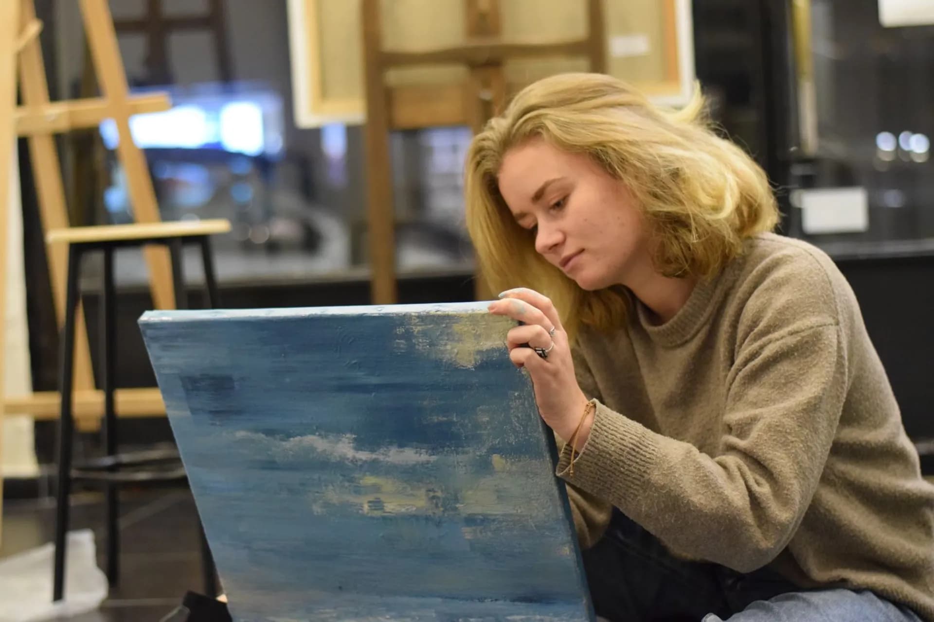 Claire Prevost au travail dans son atelier, une toile entre les mains