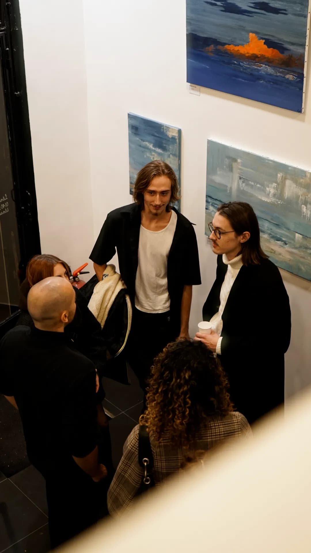 Visiteurs réunis devant les toiles pendant le vernissage de FIRST